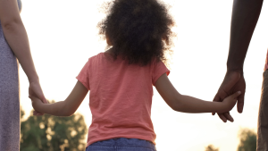 Child holding hands with two parents
