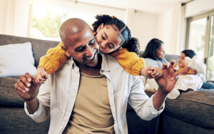 Young girl playing on her father's shoulders.